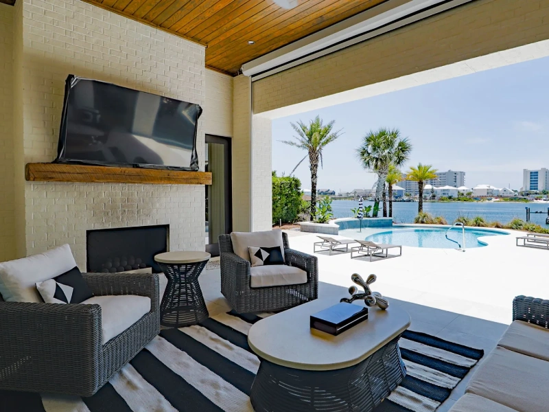 Covered terrace seating area overlooking the pool and waterfront view