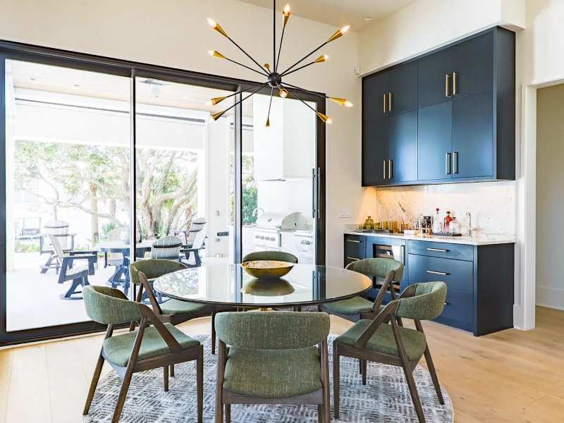 Dining area with round table, pendant lighting, sliding doors, and bar cabinetry