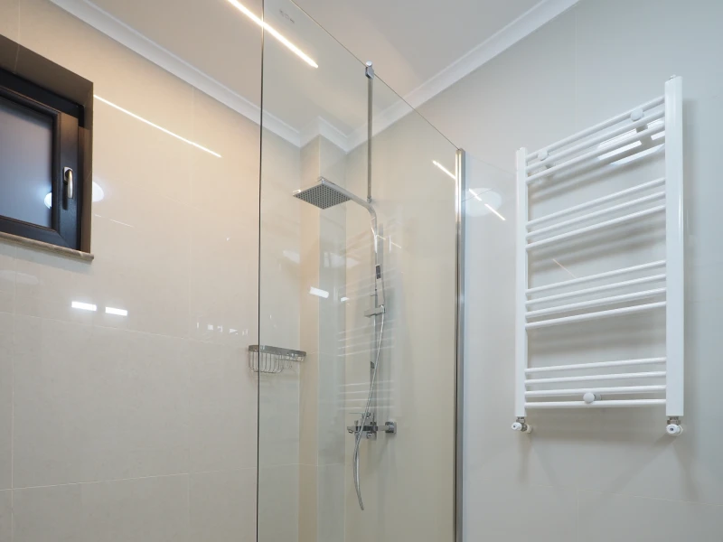 Apartment bathroom shower enclosure with glass panel and towel radiator