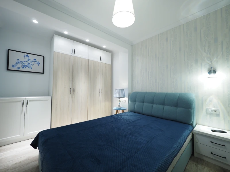 Apartment bedroom with wardrobe storage, blue bed, and compact room layout