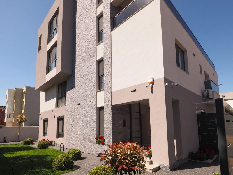 Side exterior view of a Romania apartment building with landscaped entrance area