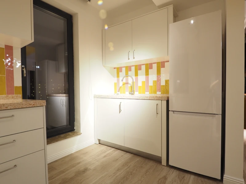 Compact kitchen cabinetry in a Romania apartment with tall storage and countertop lighting