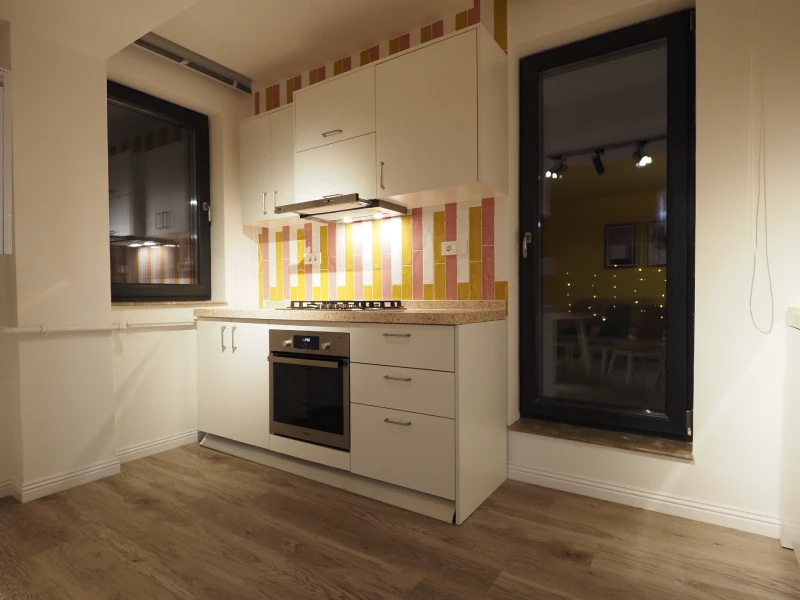 Compact apartment kitchen cabinetry with white cabinets and dark countertop
