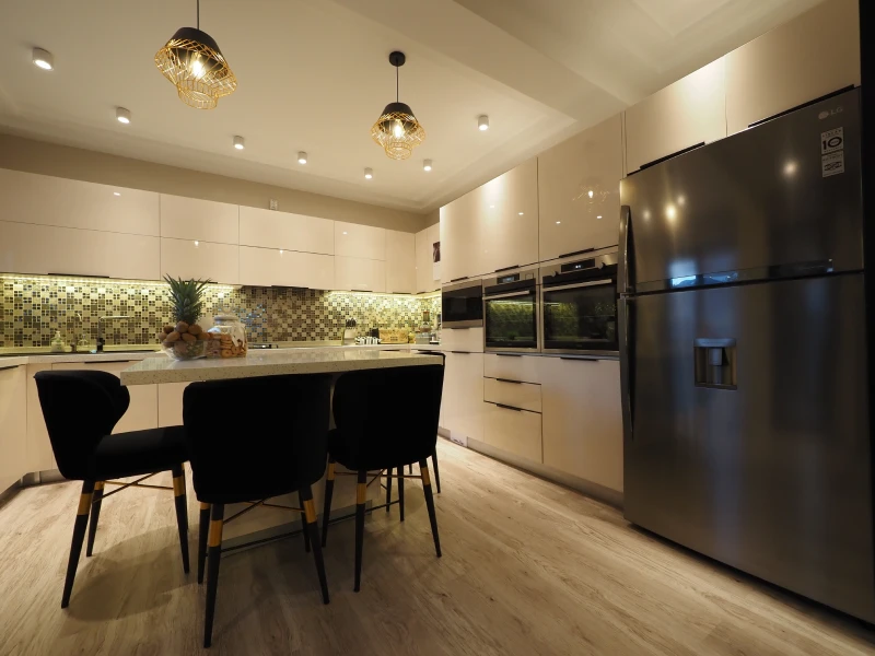 Apartment kitchen and dining area with cabinetry, pendant lighting, and dark finishes