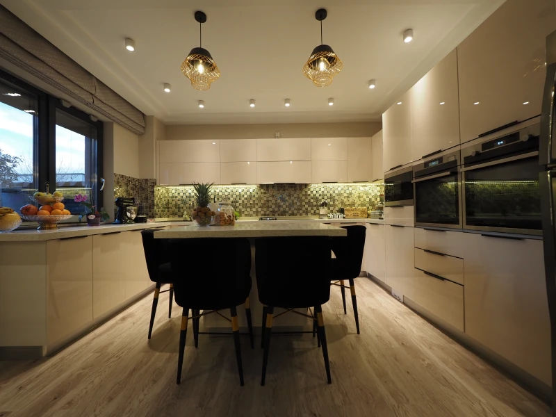 Modern apartment kitchen cabinets with dark panels, island seating, and warm lighting