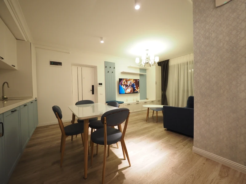 Compact apartment living and dining area with kitchen view and light flooring