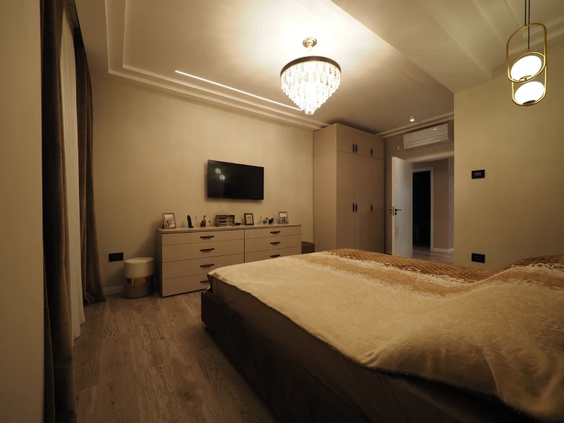 Warm apartment bedroom interior with bed, lighting, and coordinated finishes